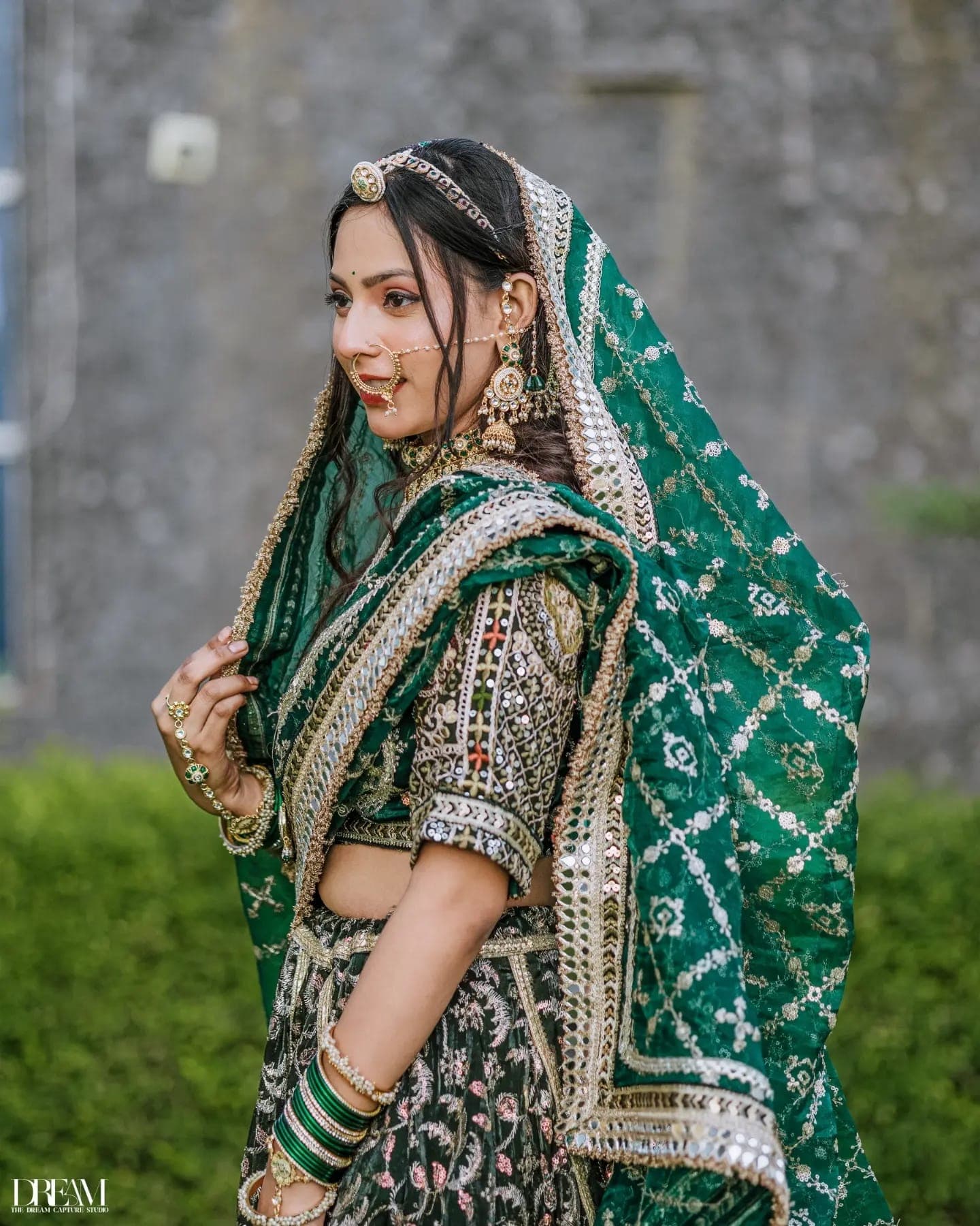 Side profile of a model in an embroidered emerald dupatta and gold jewellery