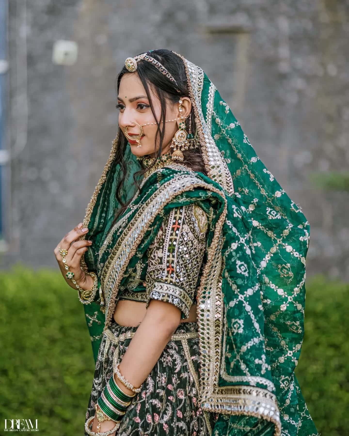 Side profile of a model in an embroidered emerald dupatta and gold jewellery
