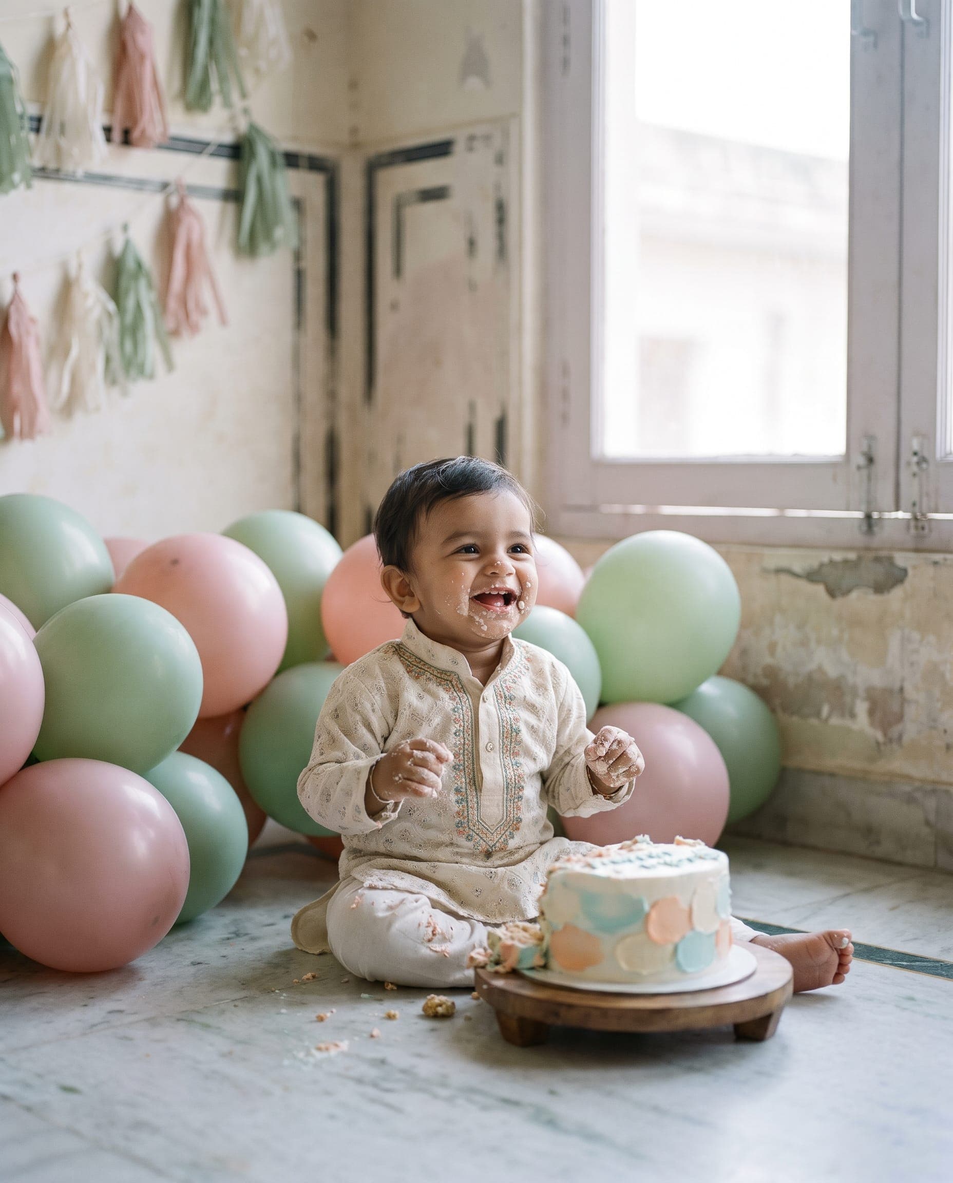 A one-year-old laughs during a cake smash shoot in the studio